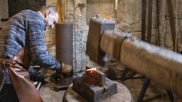 An elderly blacksmith in Austria's Salzburg region passionately upholds the centuries-old traditions of blacksmithing, working skillfully in his rustic workshop