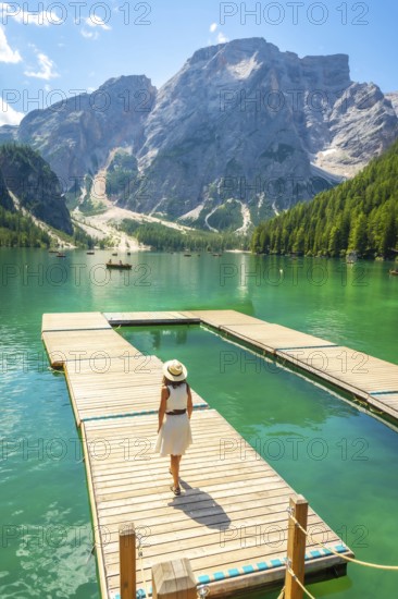 Woman enjoying a sunny summer day at lake braies, with the stunning seekofel mountain rising majestically in the background