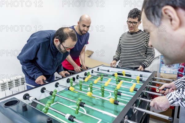 A group of people enjoy a friendly game of foosball at a mental health residence. The activity encourages social interaction, inclusion and well-being in an attractive and supportive environment