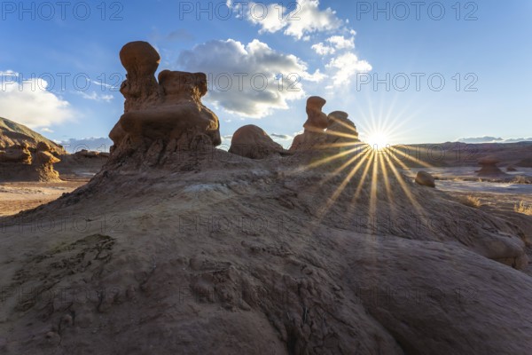 Dramatic sandstone formations in Goblin Valley State Park, Utah, USA, are illuminated by the setting sun. The natural rock sculptures create a stunning desert landscape
