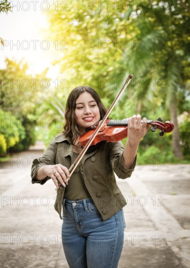 Portrait of a girl playing the violin outdoors, Close up of a girl with her violin playing a melody outdoors, Young woman playing the violin outdoors. Concept of smiling female violinist