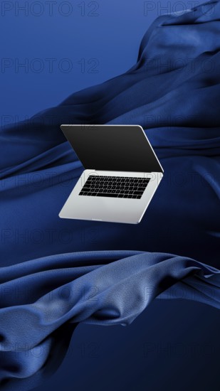 A sleek laptop is placed atop smooth fabric, showcasing its lightweight design against a rich blue backdrop