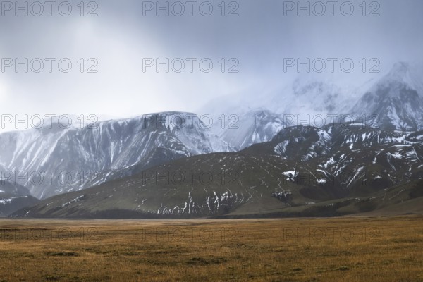 Experience the breathtaking beauty of Iceland's Highlands, featuring vast plains and majestic snow-capped mountains under a moody sky. Perfect for nature enthusiasts and photographers