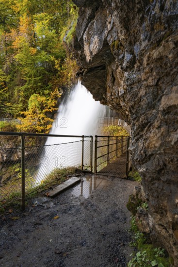 View from a rocky path to a waterfall surrounded by autumn foliage, Lake Brienz, Giessbach Waterfall, Switzerland