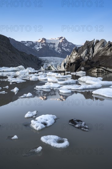 Reflection in the Svínafellslon glacier lagoon with ice floes, Svínasfellsjökull glacier tongue, glaciated mountain peak Hrútfjallstindar in the background, at sunset, Svínafell, Iceland