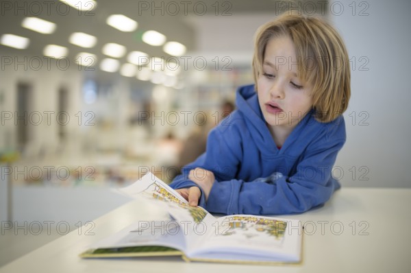 Interior shot, boy, 6 years old, blonde, reading book in the children's section of the city library, architect Eun Young Yi, Stuttgart, Baden-Württemberg, Germany