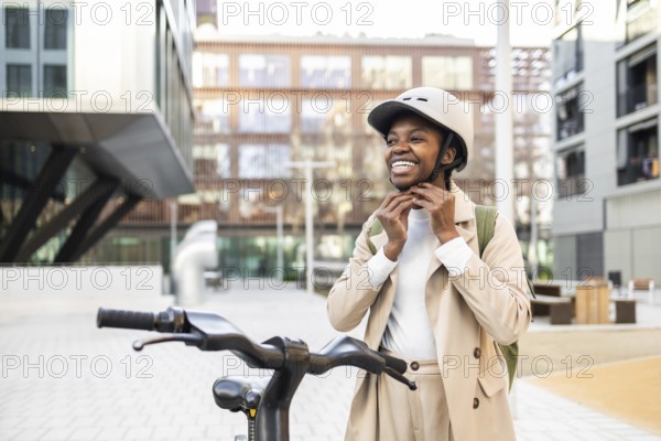 A cheerful black woman secures her helmet while standing next to a bicycle in the city The scene captures the essence of urban life and modern commuting