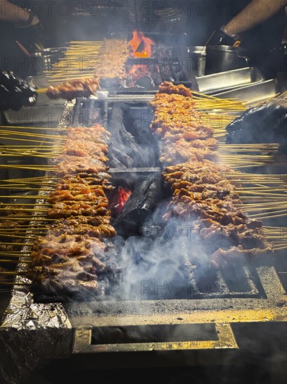 Satay, Asian food, dish which is seasoned, skewered and grilled meat over hot burning charcoal on a large satay BBQ. Delicious tasty Asian street food served with sauce for lunch or dinner. Singapore