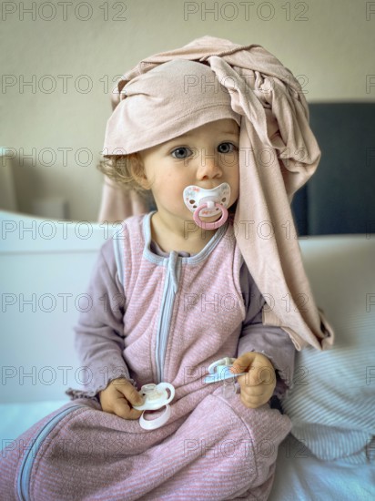 Child in pyjamas with dummy and scarf, lovingly and playfully depicted