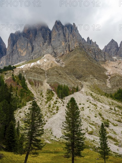 Geisler peaks rise above the rock layers into the cloudy sky, Villnöss Valley, Sass Rigais, Dolomites, South Tyrol, Italy