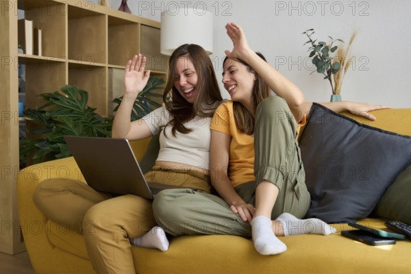 A cheerful lesbian couple relaxes on a cozy yellow sofa, smiling and enjoying quality time together Showcasing love and happiness in an inclusive LGBTQIA+ setting