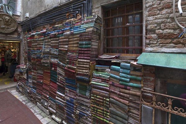 Stacked books on a wall after flood damage in a bookstore, Venice, Veneto, Italy