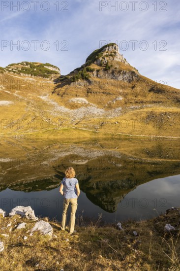 Lake Augstsee and the Atterkogel mountain on the Loser. A hiker stands on the shore. Autumn, good weather, blue sky. Reflection. Altaussee, Bad Aussee, Ausseer Land, Totes Gebirge, Styria, Upper Austria, Austria