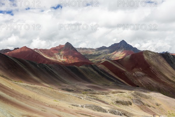 A remarkable landscape of Vinicunca, known as the Rainbow Mountain, featuring striking naturally colored mineral layers under a dynamic sky in Peru