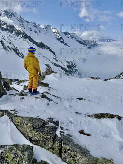 Skier enjoying the view of a valley with clouds, mountain scenery in winter, Fellilucke, Glarner Alps, Grisons, Switzerland