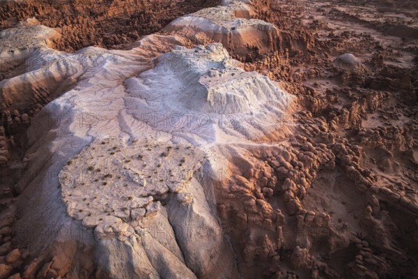 Aerial view capturing the mystical landscape of Goblin Valley State Park in Utah, USA, featuring distinctive layered rock formations and hoodoos bathed in warm sunset light
