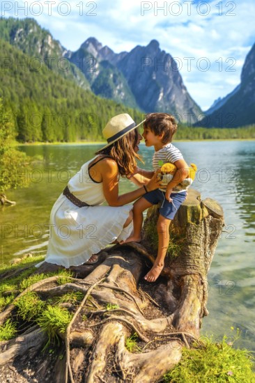 Mother and son bonding on the shore of a picturesque alpine lake, surrounded by breathtaking mountain scenery