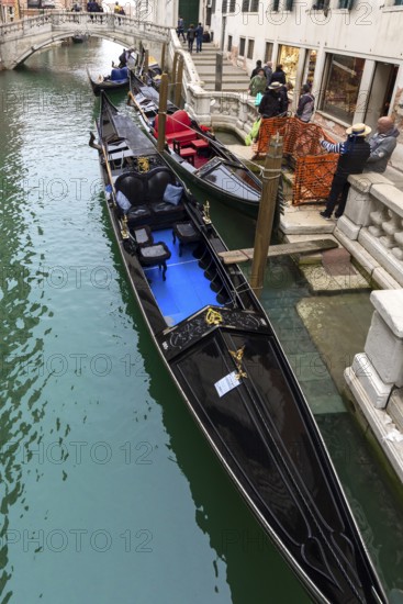 Gondoliers waiting for customers at their gondolas, Venice, Veneto, Italy