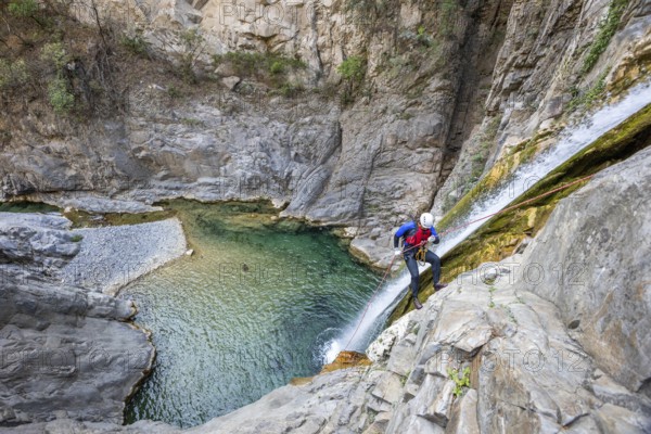 A canyoneer rappels down steep cliffs next to a waterfall, surrounded by breathtaking natural beauty, in Matacanes, Nuevo Leon, Mexico