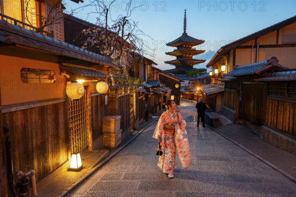 Japanese woman in kimono in an alley, Yasaka dori historic alleyway in the old town with traditional Japanese houses, five-story Yasaka Pagoda of the Buddhist Hokanji Temple in the back, evening mood, blue hour, Higashiyama, Kyoto, Japan