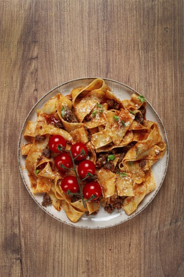 Pappardelle pasta with bolognese sauce, topped with parmesan cheese and cherry branch, homemade, no people