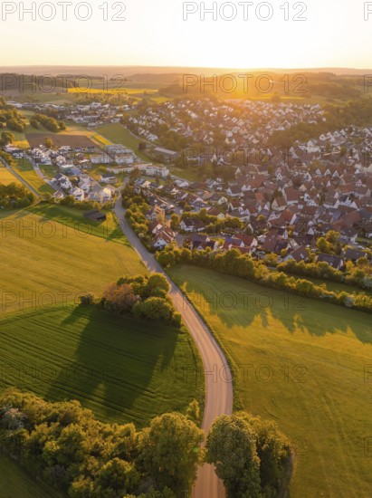 View of a village and a road surrounded by fields and trees at sunset, Gechingen, Black Forest, Germany
