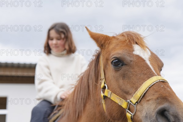 A young girl enjoys a peaceful day at the farm, riding a gentle horse. The scene captures the joy of bonding with nature and animals, emphasizing the beauty of rural life