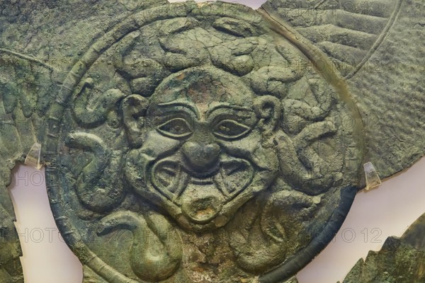 Winged gorgoneion acroterion, roof decoration from the Temple of Hera, an antique metallic face with decorated details and green patina, Olympia Archaeological Museum, Ancient Olympia, Olympia, Peloponnese, Greece
