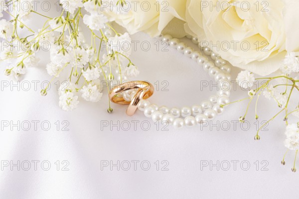 Elegant wedding rings lie nestled among delicate white roses and dainty baby's breath. The sophisticated arrangement exudes romance and timeless beauty, perfect for a wedding theme