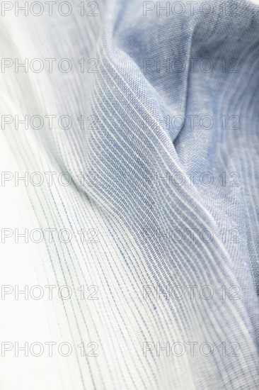 Fragment of blue and white linen tissue. Side view, textile blurred background and texture. Water and wave concept