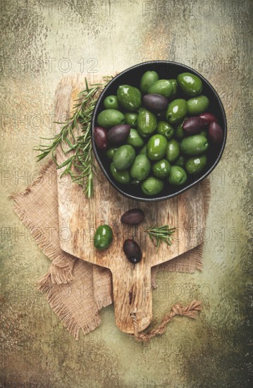 Chalkidiki olives, classic Greek green olives, in a bowl on a cutting board, top view, without people