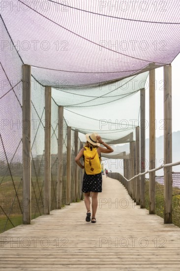 Summer vacation lifestyle. Young adventurous Caucasian girl in a hat strolling along a boardwalk