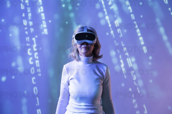 An elderly Asian woman, wearing a VR headset, explores the metaverse, surrounded by digital graphics. She experiences virtual reality in a futuristic setting with blue tones
