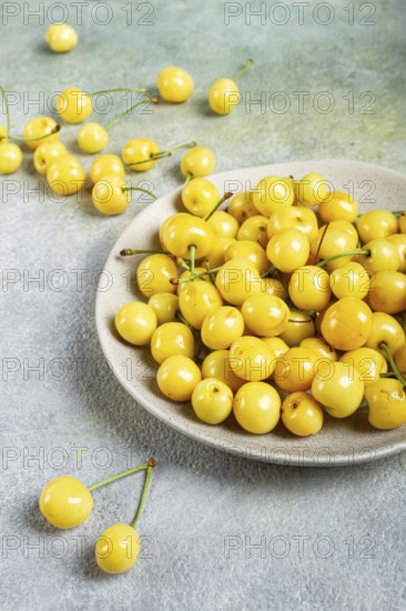 Yellow cherry, cherry berry, scattered on a plate, top view, no people