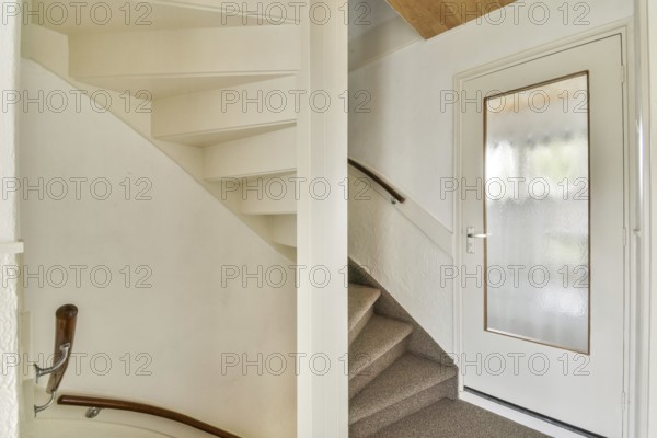 A minimalist indoor staircase with a modern design featuring light colored walls, a wooden handrail, and carpeted steps leading to the upper floor, creating a cozy atmosphere