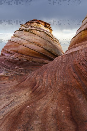 Dramatic sandstone formations with sweeping curves and layered colors captured at Coyote Buttes in the Paria Canyon-Vermilion Cliffs Wilderness, Arizona, showcasing a stunning desert landscape