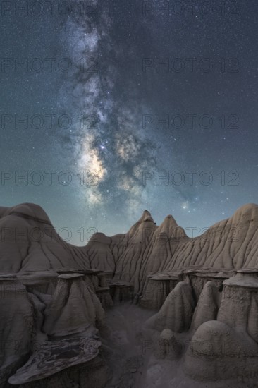 A breathtaking night sky filled with the Milky Way stretches above the unique, weathered rock formations in Utah, USA