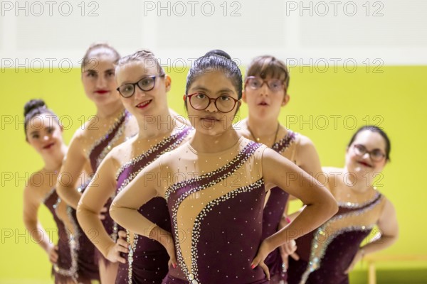 A diverse gymnastic team showcases unity and determination. Wearing matching outfits with sequins, they strike a confident pose, embodying teamwork and inclusivity in sports