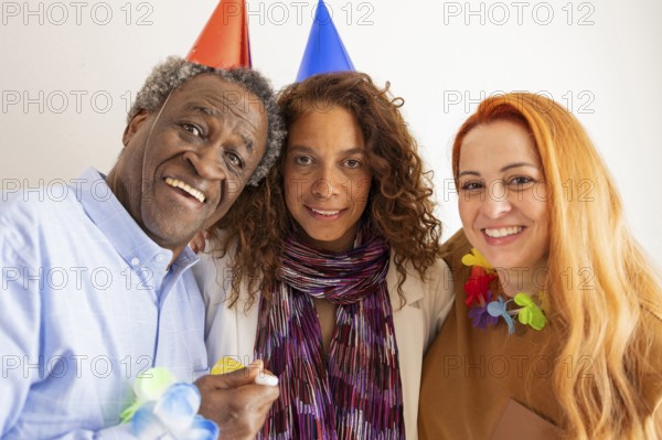 Three friends celebrate a special occasion, wearing colorful party hats and leis. Their joyful expressions capture the essence of a lively and festive birthday celebration