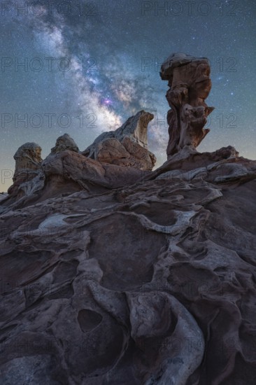 Captivating nightscape of the Milky Way illuminating the rugged desert terrain of White Pocket, Arizona, USA. The celestial brilliance contrasts with the textured rock formations