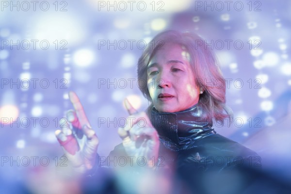 An elderly Asian woman explores the metaverse, engaging with virtual holographic displays. The image captures technology blending with daily life for older generations