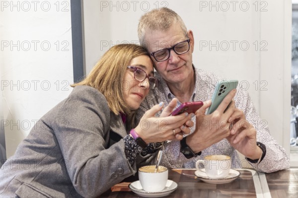 A couple with intellectual disabilities sits at a cafe table, with their smartphones. They share a moment of relaxation with two cups of coffee, showcasing a blend of technology and leisure
