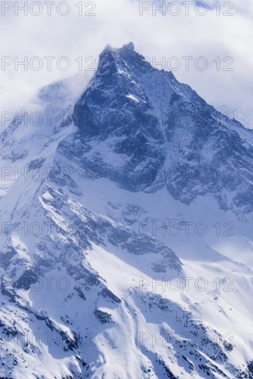 Fog envelops the snowy summit of the mountain Le Besso, Val d'Anniviers, Valais Alps, Canton Valais, Switzerland