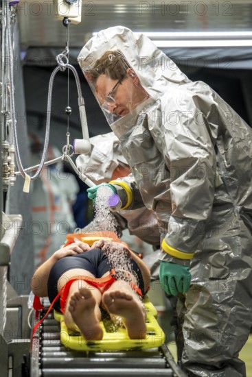 Decontamination of injured persons after an assumed accident involving hazardous substances, fire brigade and aid organisations practise setting up and operating a decontamination station, injured persons are sighted and then washed in a special shower tent to remove possible hazardous substances and chemicals in order to avoid further injuries, the emergency services wear special, ventilated protective suits, large-scale exercise by the Essen fire brigade