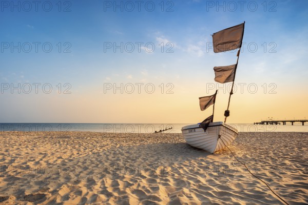 Fishing boat with black flags on a fine sandy beach in the morning light, Baltic resort Bansin, Usedom island, Mecklenburg-Western Pomerania, Germany