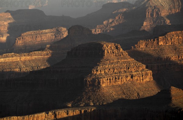 The Grand Canyon's rugged terrain is bathed in warm hues during sunset. This iconic USA landmark showcases layers of history, rock formations, and natural beauty in a breathtaking vista
