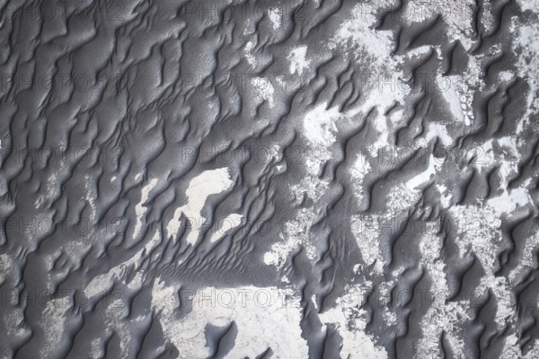 From above intricate patterns of black sand adorned with subtle white shades, creating a visually stunning textural landscape