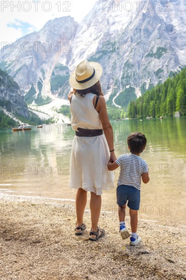 Mother and son admiring stunning panorama of lake braies, surrounded by majestic mountains and lush greenery in italian dolomites
