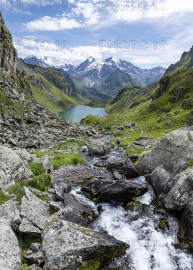 Mountain stream and mountain lake Lac de Louvie with glaciated summit of the Grand Combin, Val de Bagnes, Valais, Switzerland