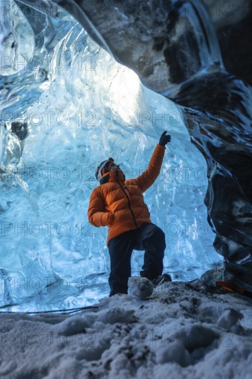 A man in an orange jacket in a glacier cave in Iceland in winter